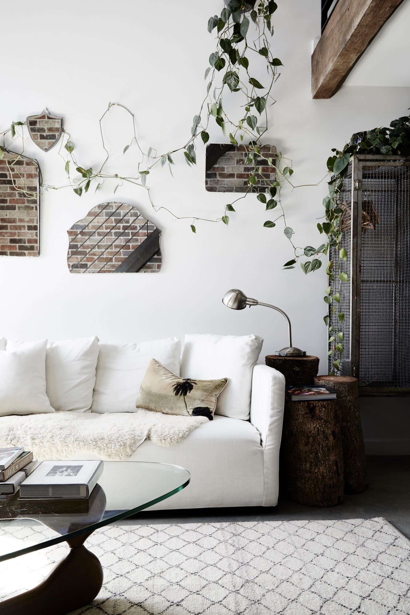 Vintage wall mirrors, trailling greenery, white linen sofa and logs used as side tables at The Chapel, Byron Beach Abodes