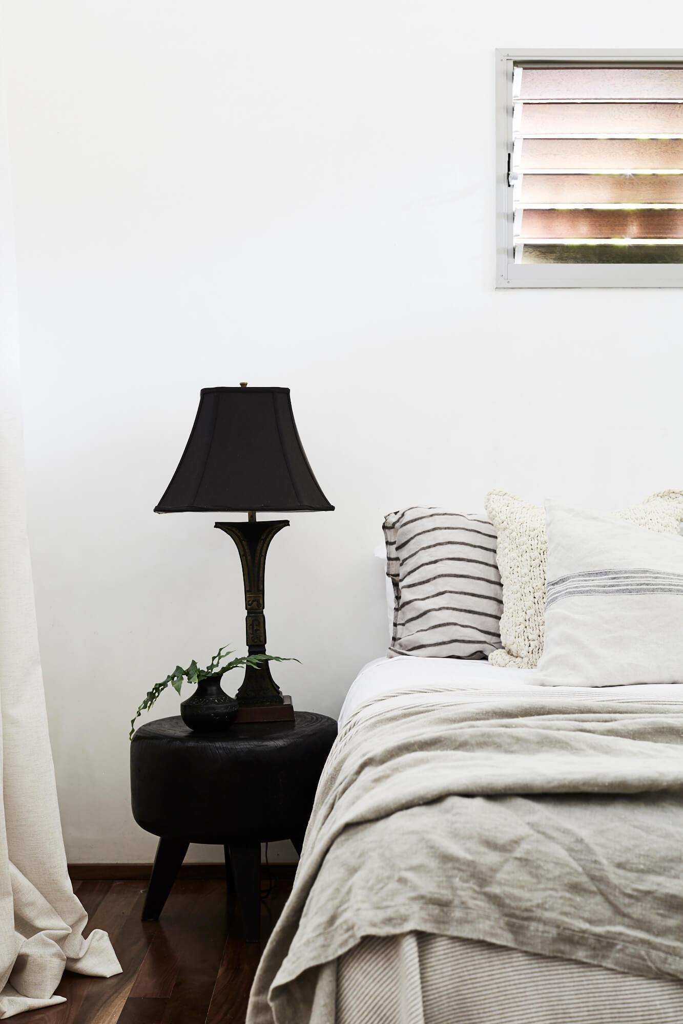 Layers of linen bedding and cushions next to a carved timber bedside table at The Villas of Byron