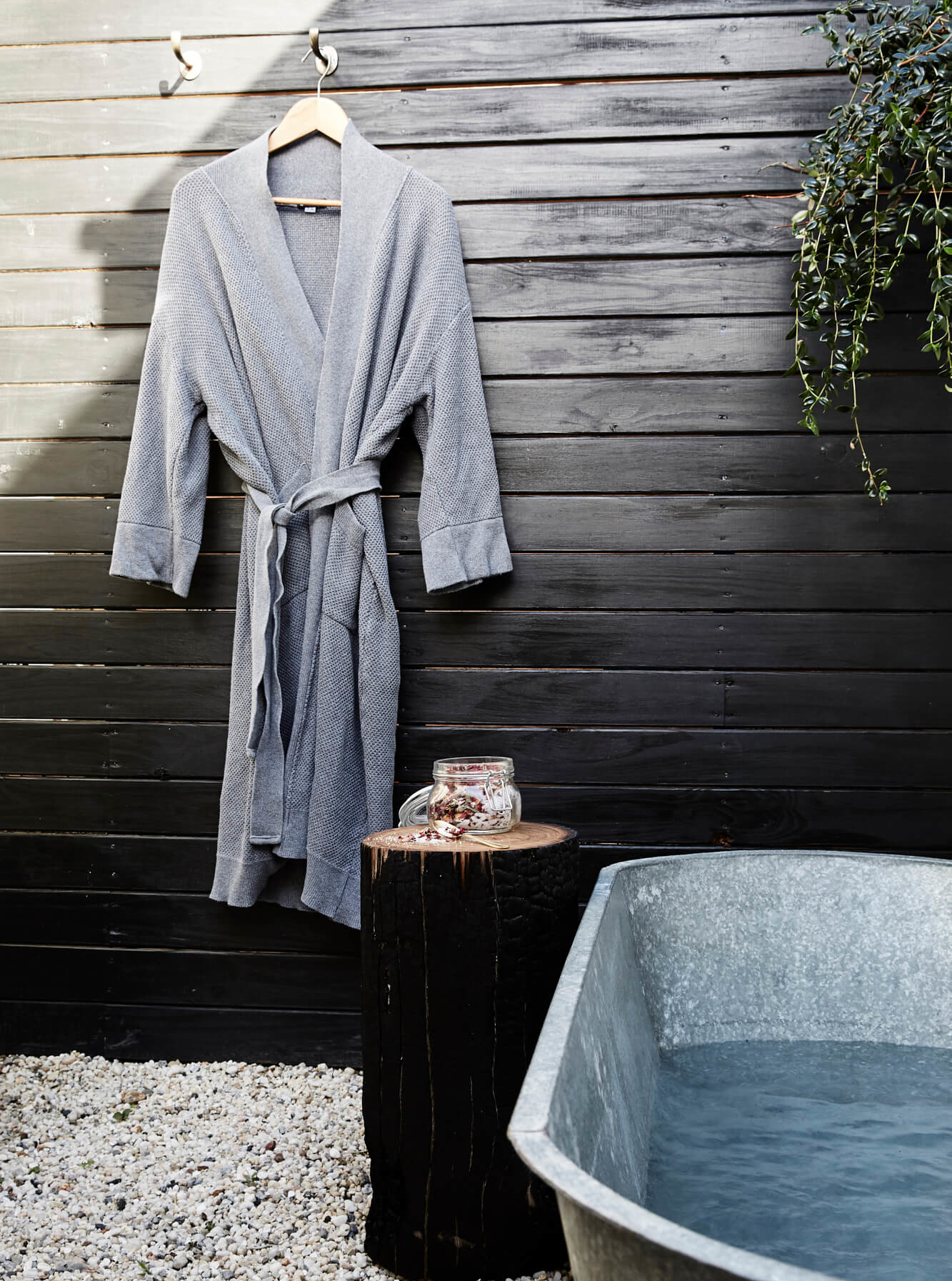 Outdoor bathroom at The Cottage, Byron Beach Abodes with tin bath, plush Bemboka bathrobe and log stool with custom hand made bath salts