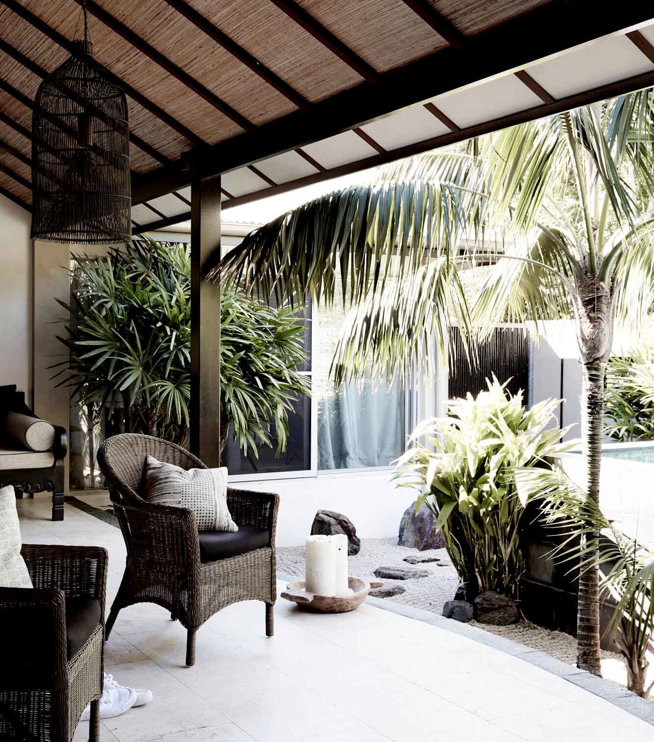 Lush outdoor area at the Grand Villa, Villas of Byron, featuring classic woven armchairs, a raked zen garden, and tropical garden landscaping