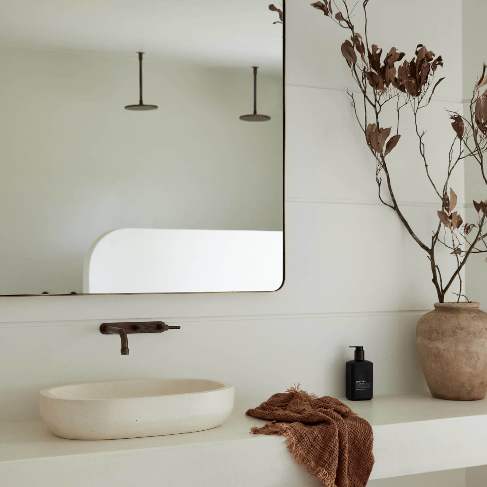 The Le Viti Barn Newrybar enquite with custom open vanity, panelled walls, curved-edge wall mirror, brushed brass fittings and stone vanity bowl