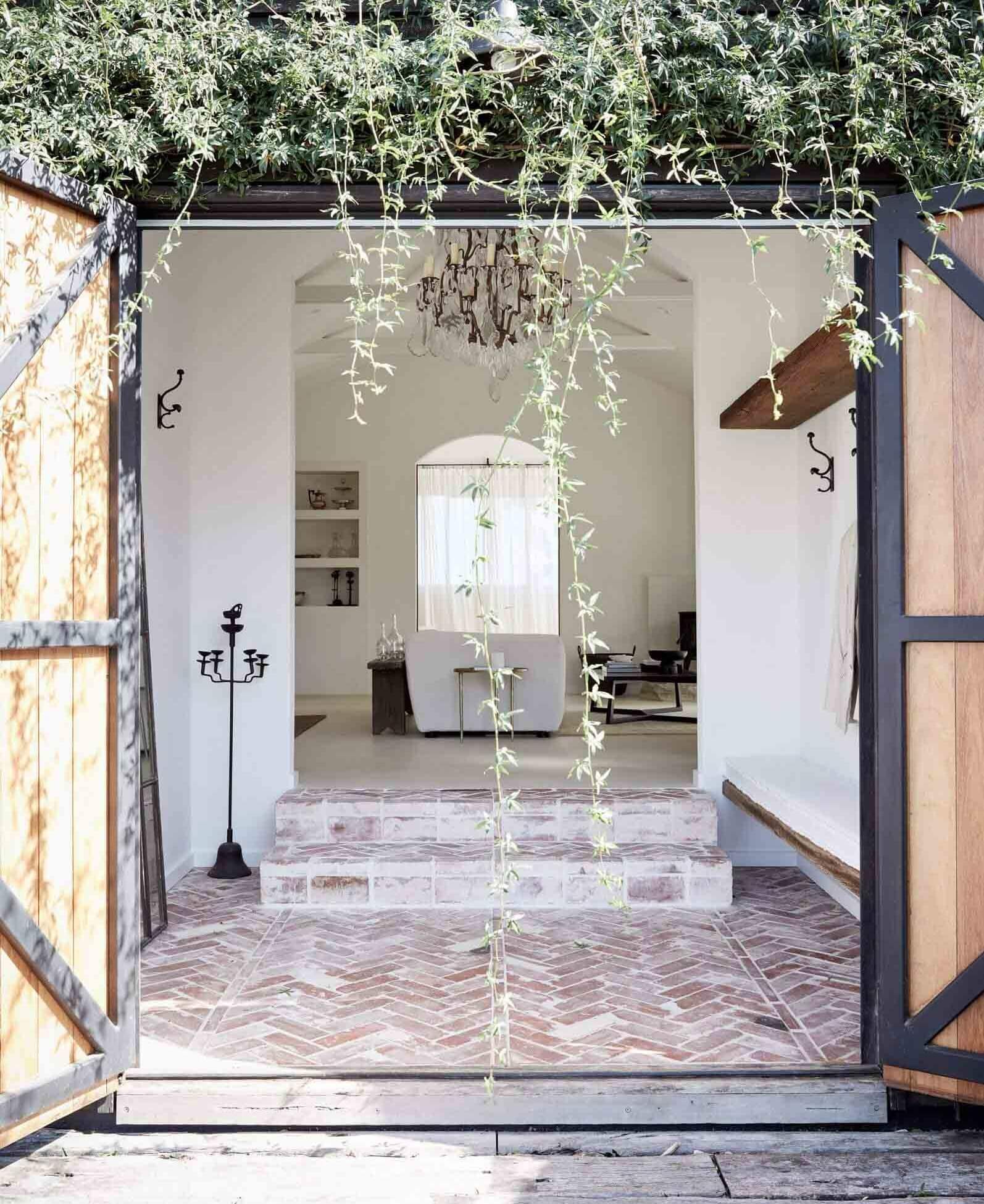 Entrance to Le Viti Barn accommodation in Newrybar with beautiful cascading greenery, rustic bricks and antique chandelier