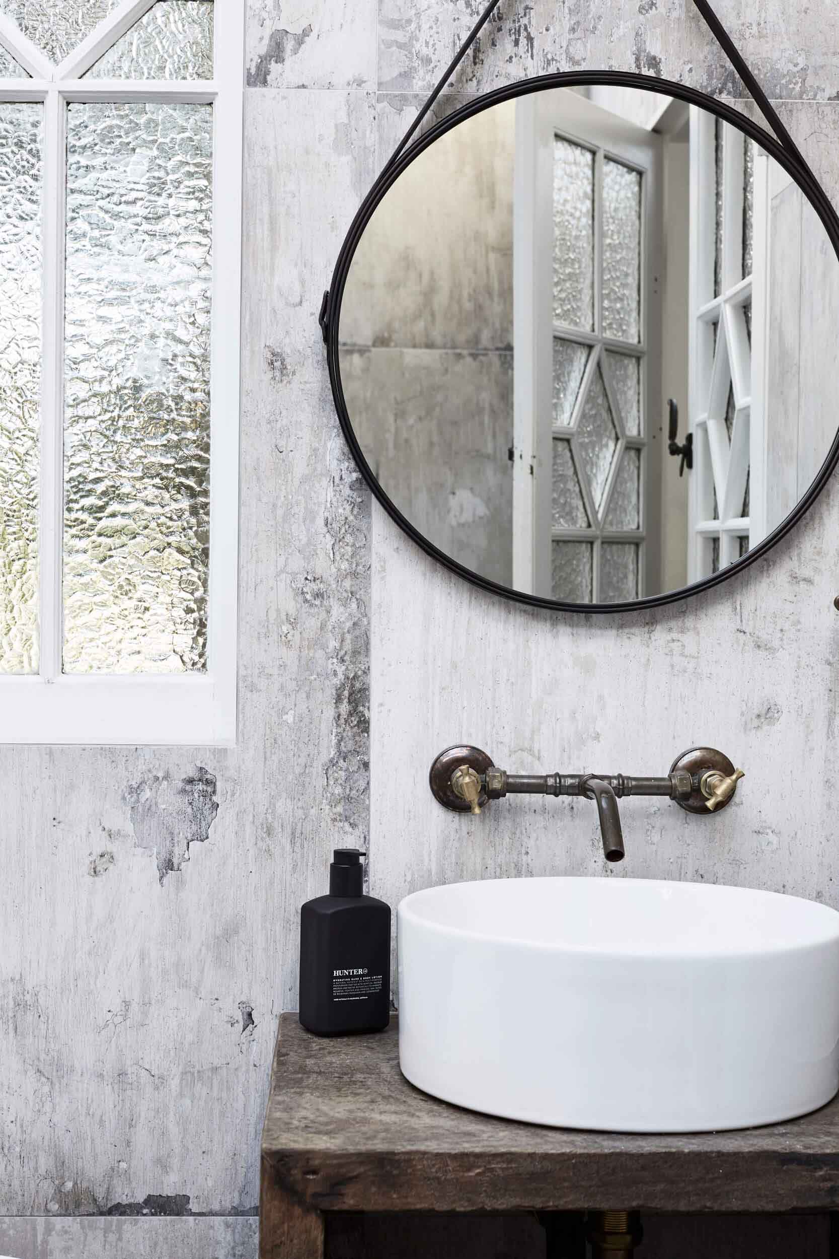 Ensuite at the Bower Barn, The Bower Byron Bay hotel with grey wall tiles, round mirror, recycled timber windows and aged-patina tapware