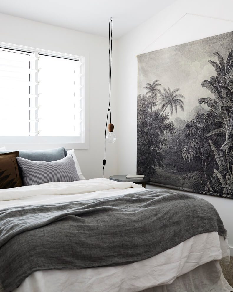 Bedroom at Magnolia House, Byron Beach Abodes with printed fabric wall hanging, and bed covered in luxe linens