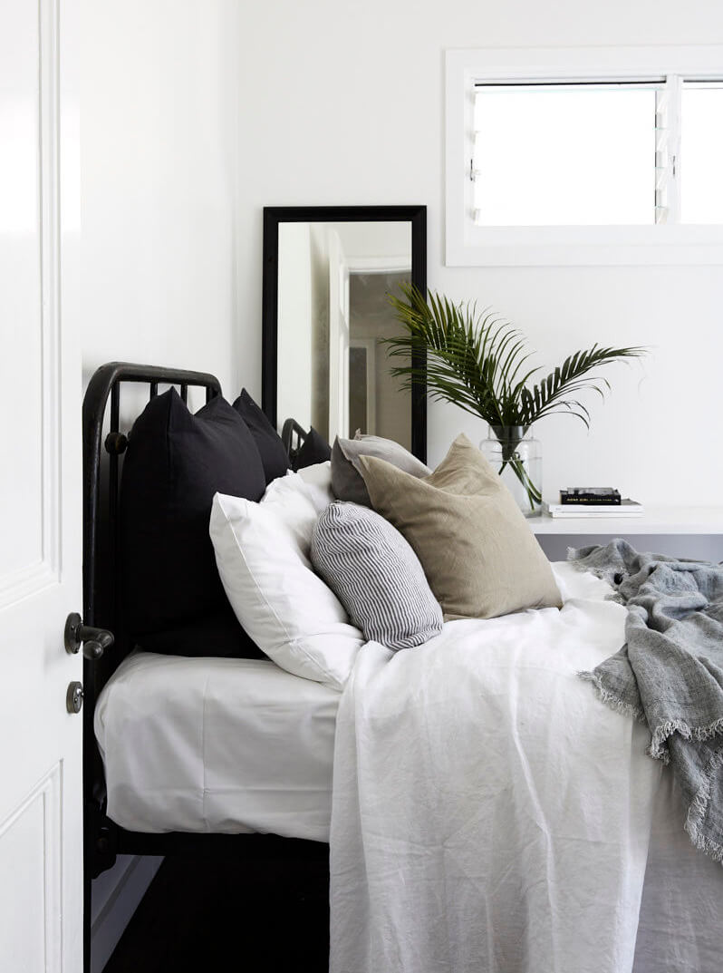 Bed layered with luxury linen, cushions and pillows at Magnolia House, Byron Beach Abodes