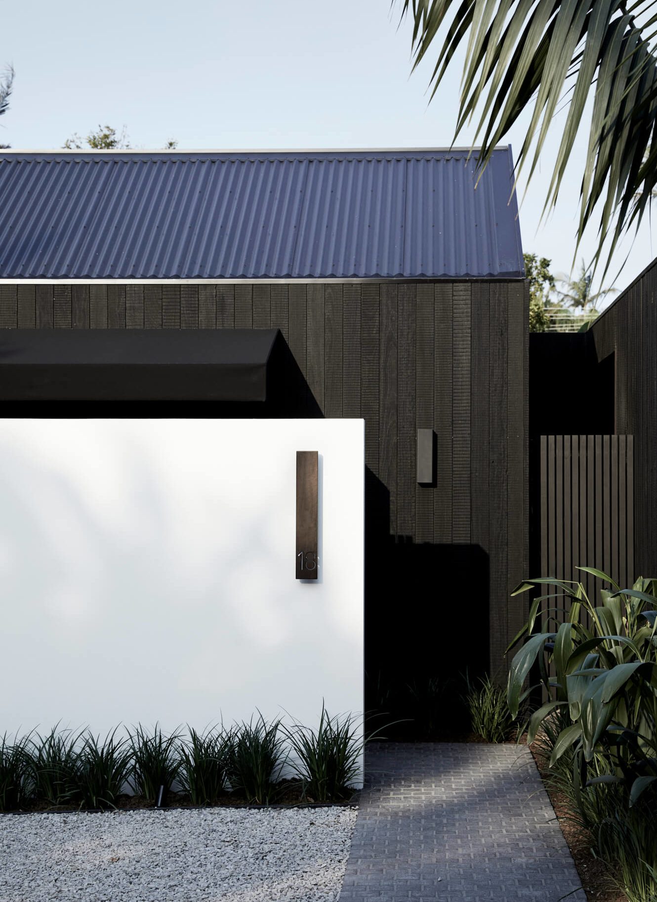 Black timber clad exterior of the Bower Studios at The Bower Byron Bay hotel against the rendered white privacy wall