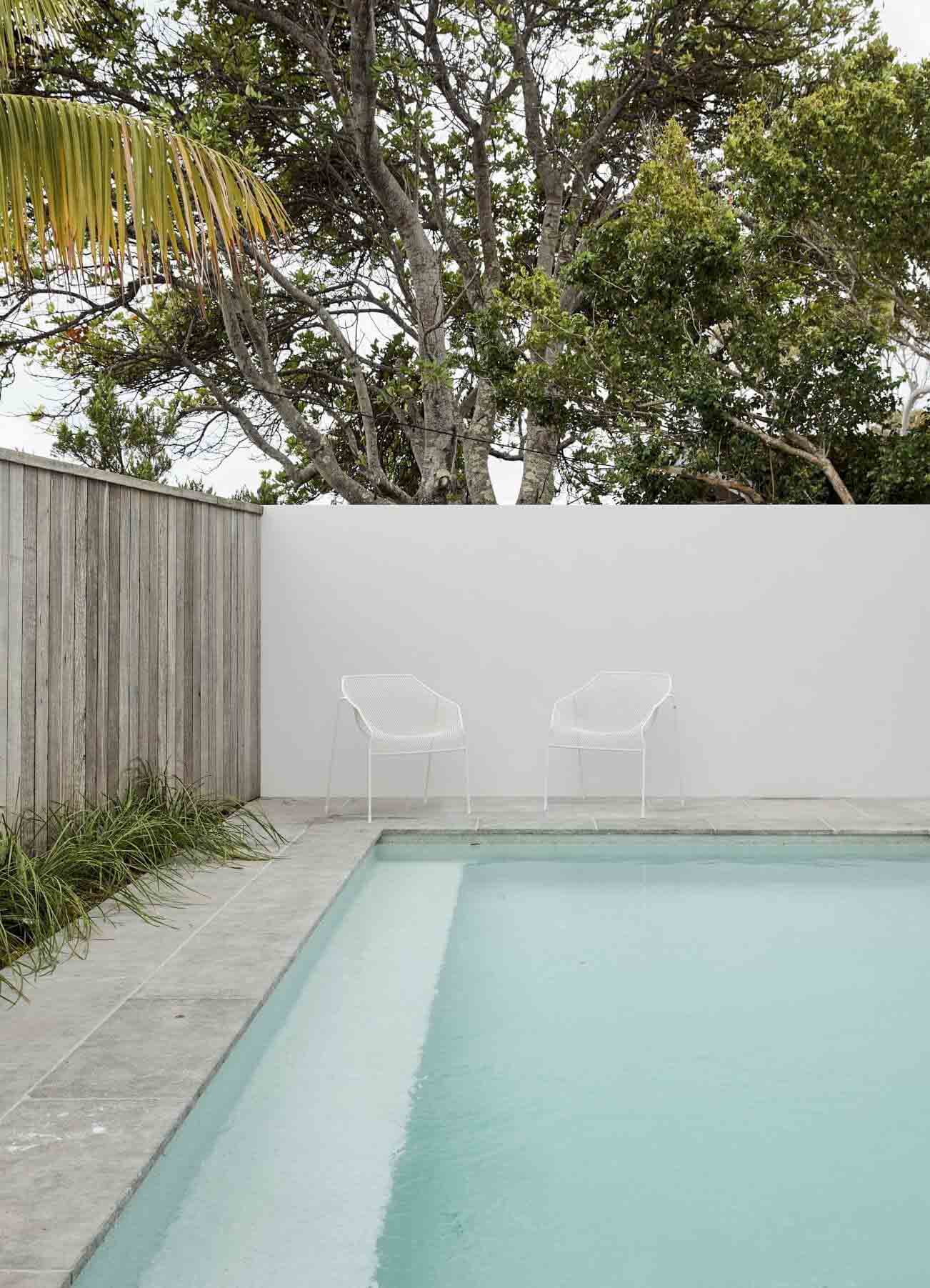 The pool at The Lodge, Byron Beach Abodes with simple landscaping, stone tiles, and rendered pool fence