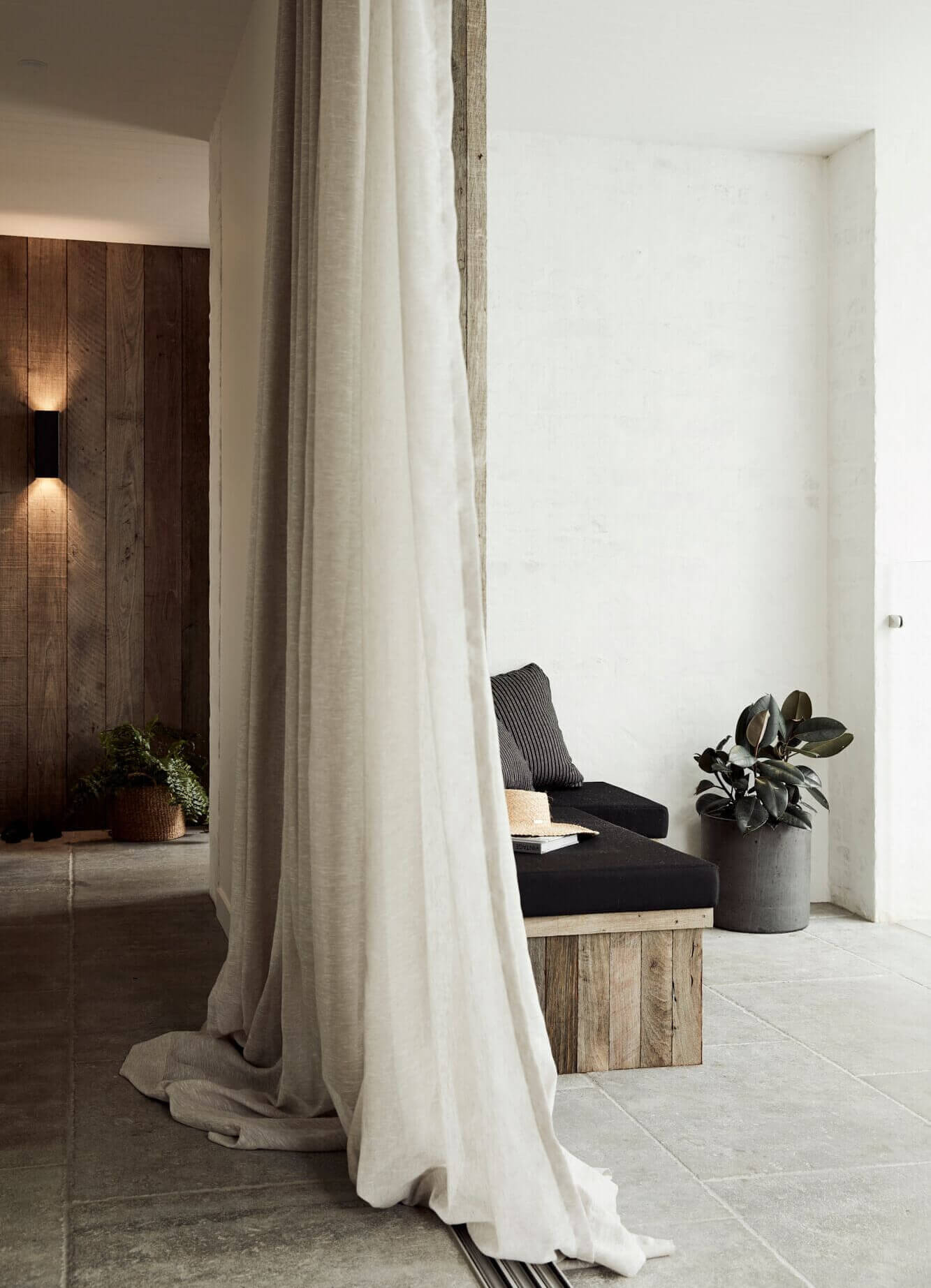 Foyer at The Lodge, Byron Beach Abodes with textured rendered or Jarrah clad walls, stone floors and floor to ceiling linen curtains