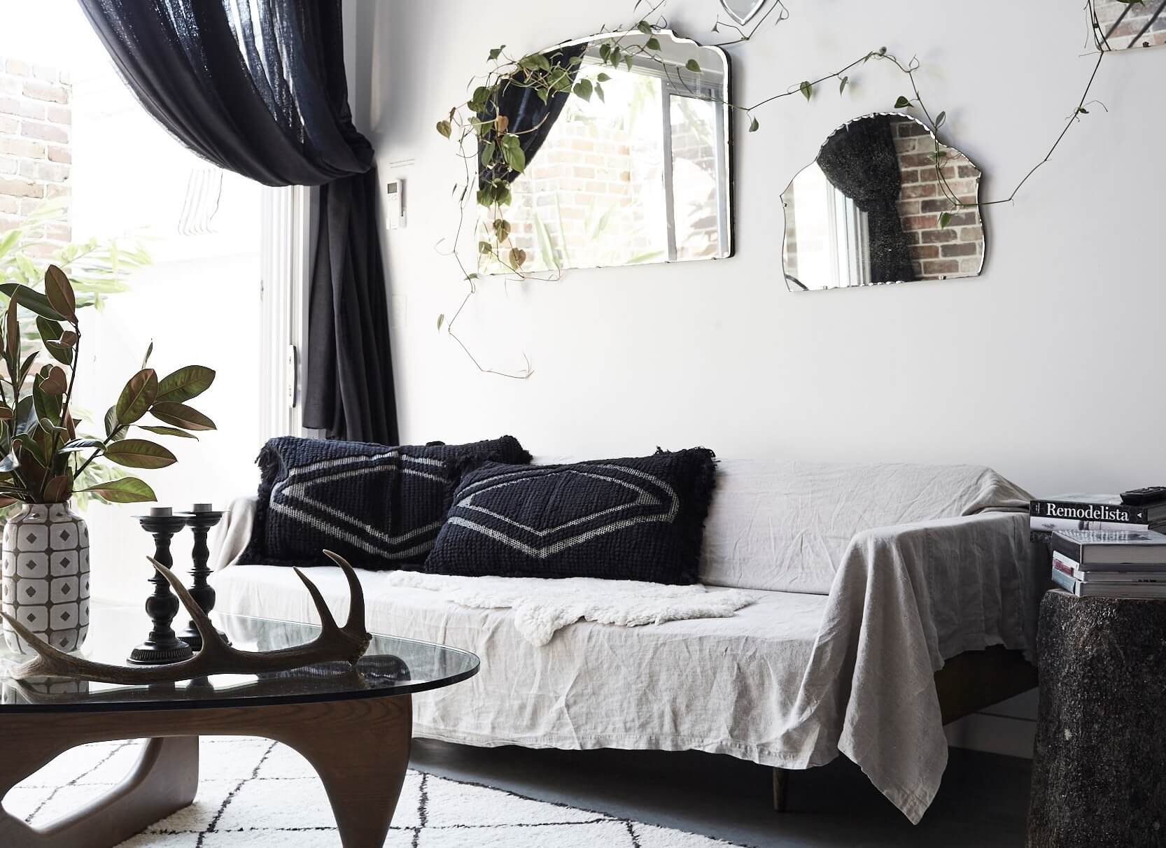 Living room at The Chapel, Byron Beach Abodes with linen-covered sofa, Kilim rug, vintage wall mirrors and greenery