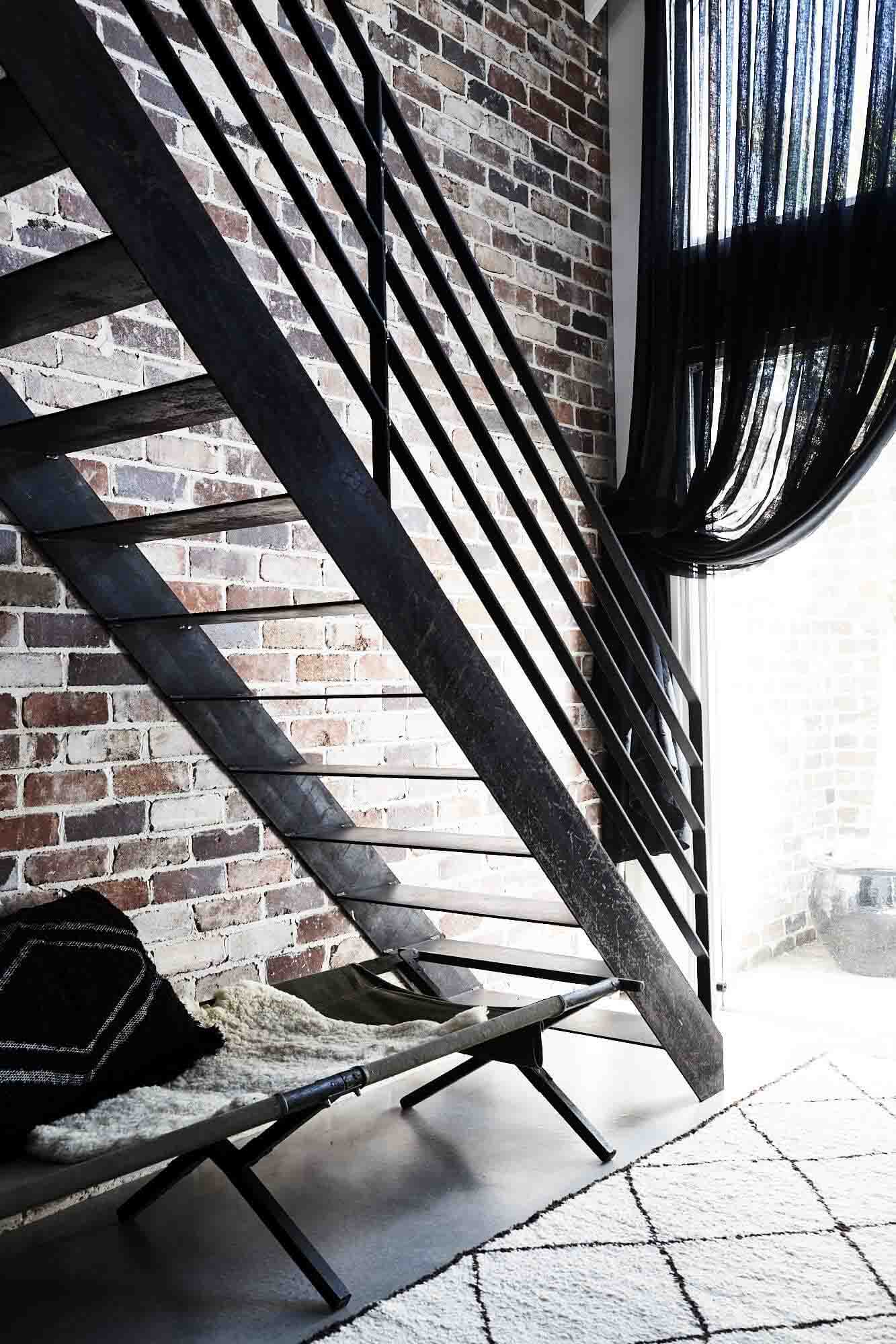 Textured materials at The Chapel, Byron Beach Abodes including raw steel staircase, exposed brick wall, and linen curtains